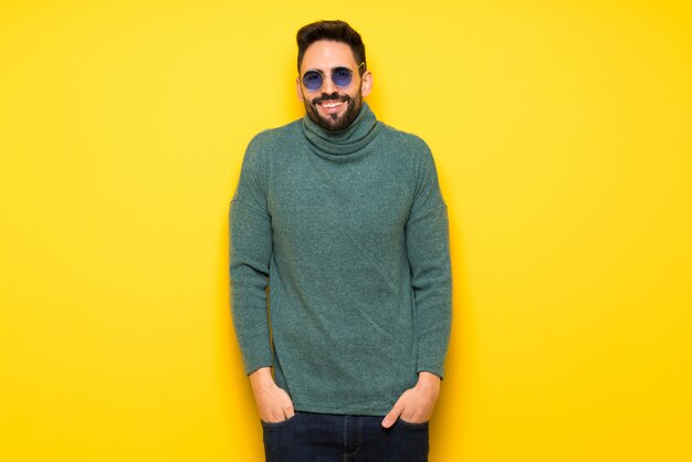 Hombre guapo con gafas de sol sonriendo mucho mientras se pone las manos en el pecho