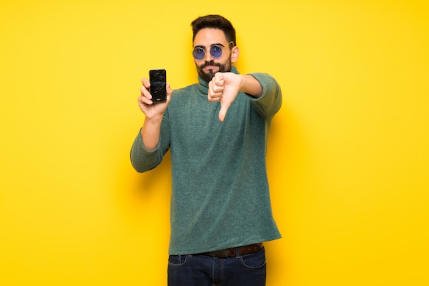 Hombre guapo con gafas de sol con teléfono inteligente roto con problemas