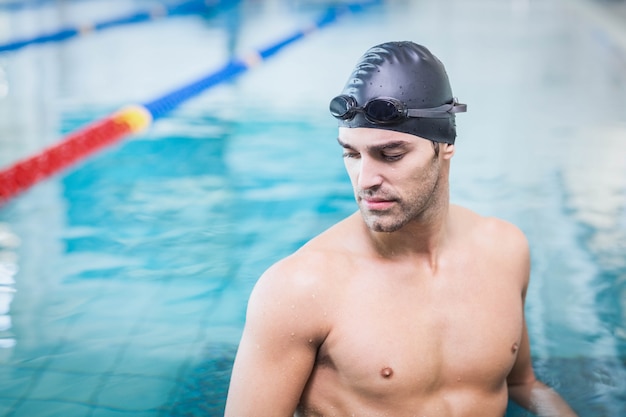 Hombre guapo con gorra de baño y gafas en la piscina