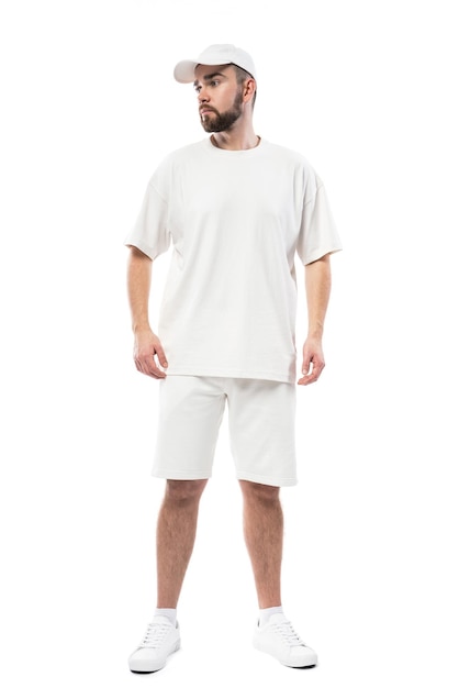 Hombre guapo con gorra blanca en blanco, camiseta y pantalones cortos aislados en fondo blanco