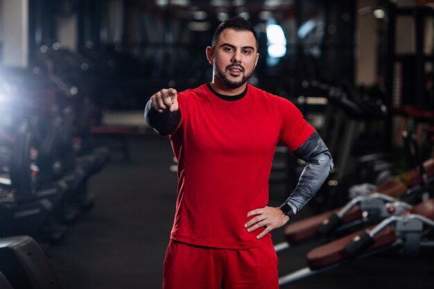 Hombre guapo con grandes músculos, posando a la cámara en el gimnasio