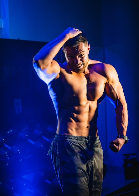 Hombre guapo con grandes músculos, posando en el gimnasio