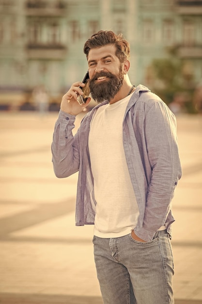 Hombre guapo habla en teléfono inteligente en la calle foto de hombre habla en teléfono móvil hombre habla en smartphone hombre al aire libre habla en teléfono electrónico afuera