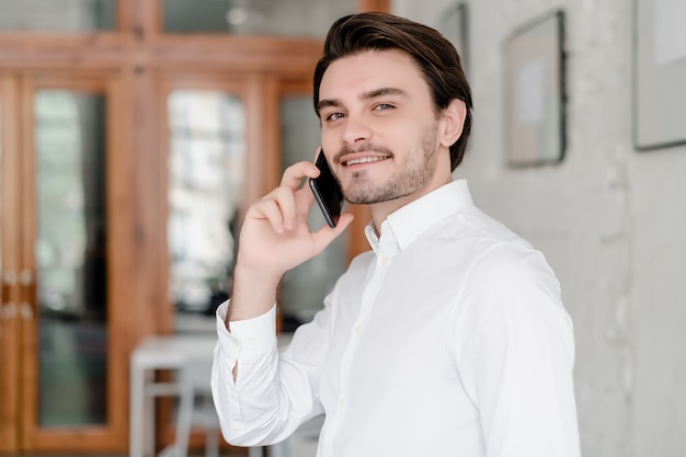 Hombre guapo hablando por teléfono en la oficina