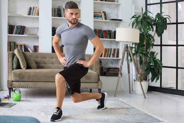 Hombre guapo haciendo ejercicio deportivo en casa durante la cuarentena. Concepto de vida sana