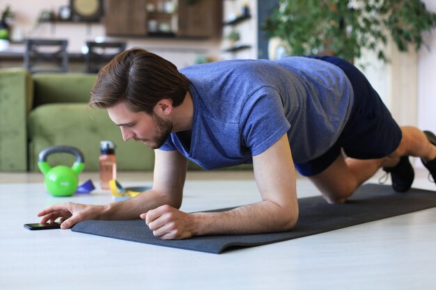 Hombre guapo haciendo ejercicio deportivo en casa durante la cuarentena. Concepto de vida sana.