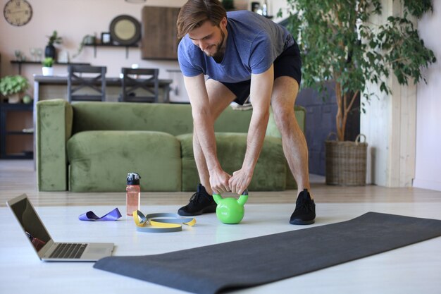 Hombre guapo haciendo ejercicio deportivo en casa durante la cuarentena. Concepto de vida sana.