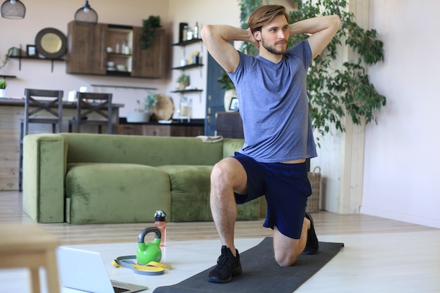 Hombre guapo haciendo ejercicio deportivo en casa durante la cuarentena. Concepto de vida sana.