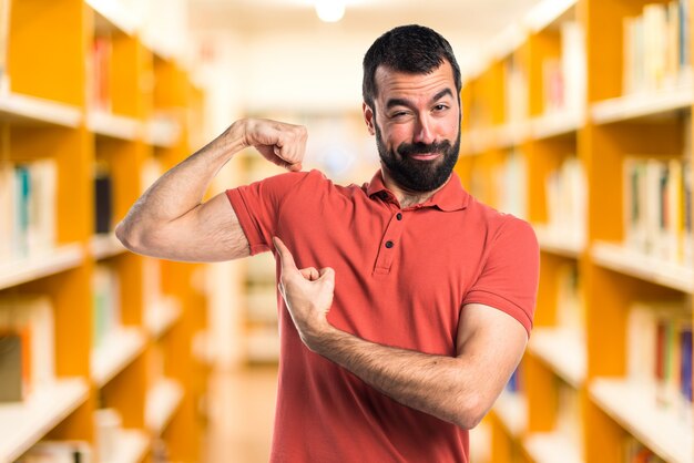 Hombre guapo haciendo gesto fuerte sobre fondo desenfocado