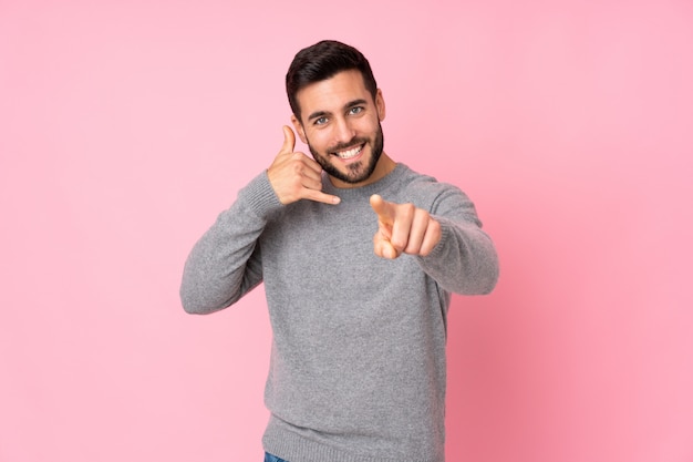 hombre guapo haciendo gesto de teléfono y apuntando hacia delante