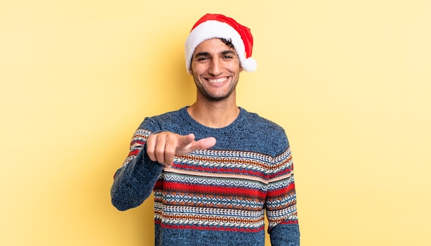 Hombre guapo hispano apuntando a la cámara eligiéndote. concepto de navidad