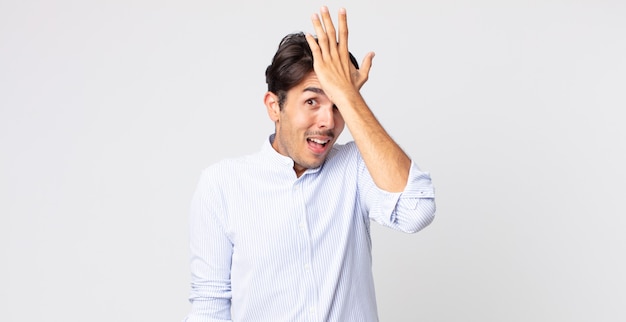 Hombre guapo hispano levantando la palma de la mano a la frente pensando Uy, después de cometer un error estúpido o recordar, sentirse tonto