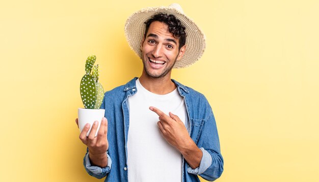 Hombre guapo hispano que parece emocionado y sorprendido apuntando al concepto de agricultor y cactus de lado