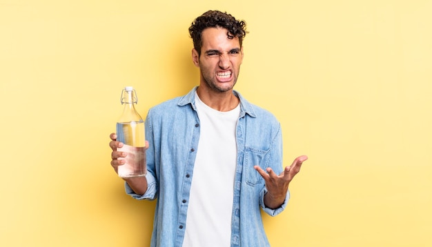 Hombre guapo hispano que parece enojado, molesto y frustrado. concepto de botella de agua