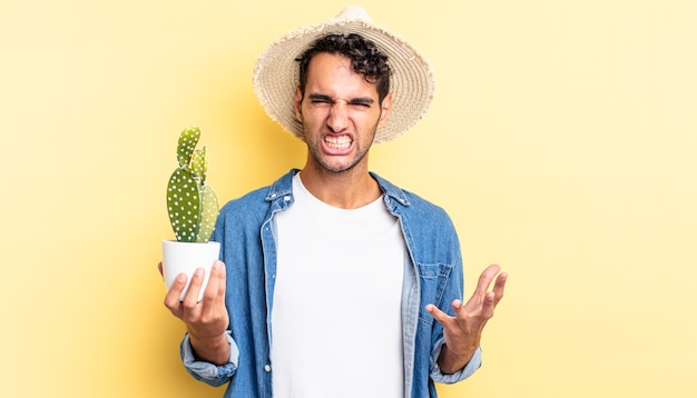 Hombre guapo hispano que parece enojado, molesto y frustrado granjero y concepto de cactus