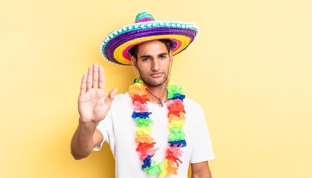 Hombre guapo hispano que parece serio mostrando la palma abierta haciendo gesto de parada. concepto de fiesta mexicana