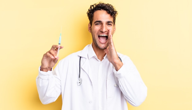 Hombre guapo hispano que se siente feliz, dando un gran grito con las manos junto al médico de la boca y el concepto de srynge