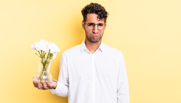 Hombre guapo hispano que se siente triste y quejumbroso con una mirada infeliz y llorando. concepto de maceta de flores