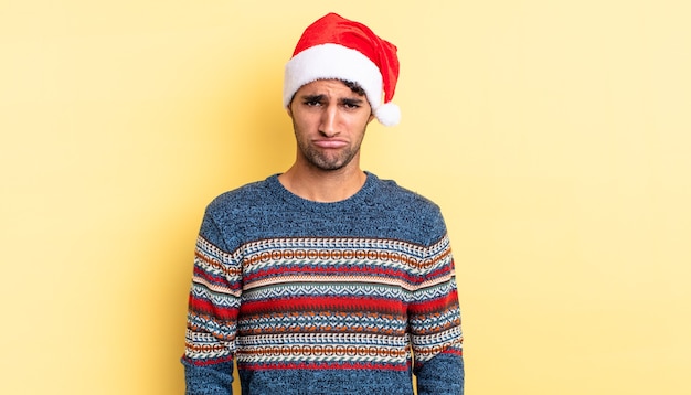 Hombre guapo hispano que se siente triste y quejumbroso con una mirada infeliz y llorando. concepto de navidad