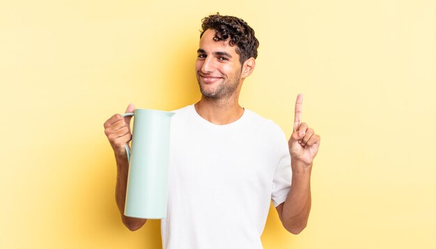 Hombre guapo hispano sonriendo y mirando amistoso, mostrando el número uno. concepto de termo de café