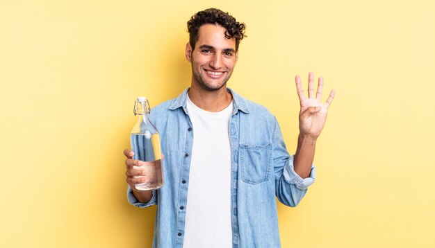 Hombre guapo hispano sonriendo y mirando amistoso, mostrando el número cuatro. concepto de botella de agua