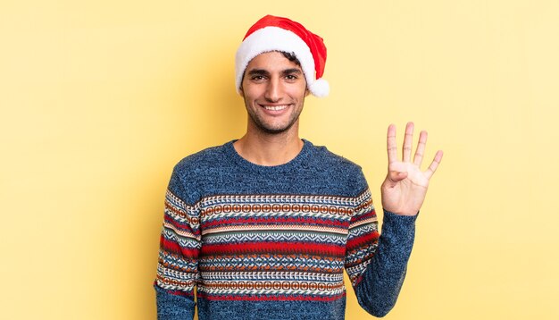 Hombre guapo hispano sonriendo y mirando amistoso, mostrando el número cuatro. concepto de navidad