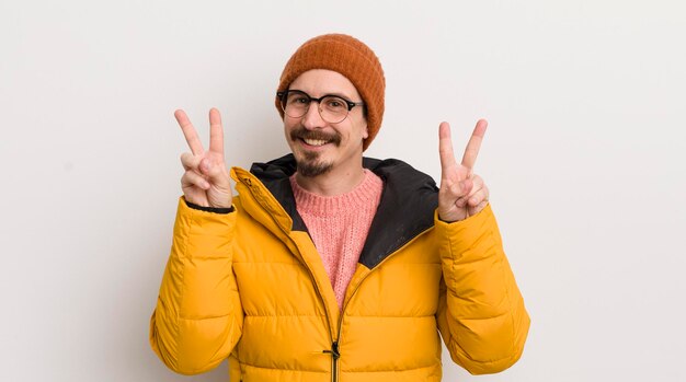 Hombre guapo joven con un abrigo contra la pared blanca