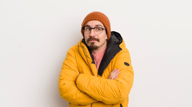 Hombre guapo joven con un abrigo contra la pared blanca