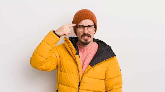 Hombre guapo joven con un abrigo contra la pared blanca