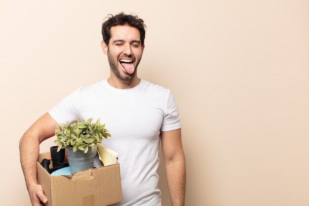 Hombre guapo joven con actitud alegre, despreocupada, rebelde, bromeando y sacando la lengua, divirtiéndose