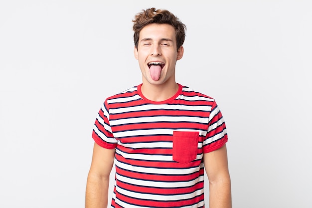 Hombre guapo joven con actitud alegre, despreocupada, rebelde, bromeando y sacando la lengua, divirtiéndose