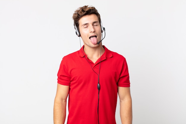 Hombre guapo joven con actitud alegre y rebelde, bromeando y sacando la lengua. concepto de telemarketer