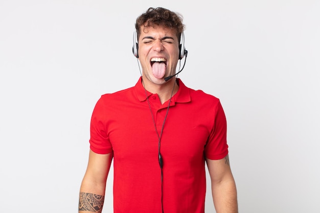 Hombre guapo joven con actitud alegre y rebelde, bromeando y sacando la lengua. concepto de telemarketer