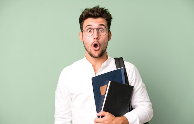 Hombre guapo joven aislado con un concepto de estudiante universitario de bolsa y libros