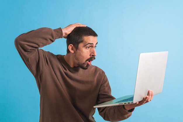 Hombre guapo joven aislado sobre fondo azul usando su computadora portátil trabajando Copiar texto de espacio