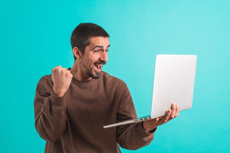 Foto hombre guapo joven aislado sobre fondo azul usando su computadora portátil trabajando copiar texto de espacio