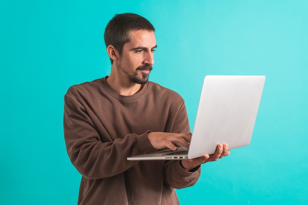 Hombre guapo joven aislado sobre fondo azul usando su computadora portátil trabajando Copiar texto de espacio