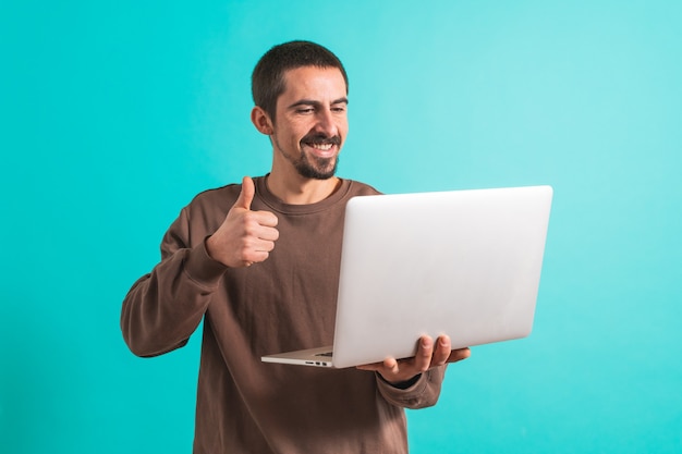 Hombre guapo joven aislado sobre fondo azul usando su computadora portátil trabajando Copiar texto de espacio