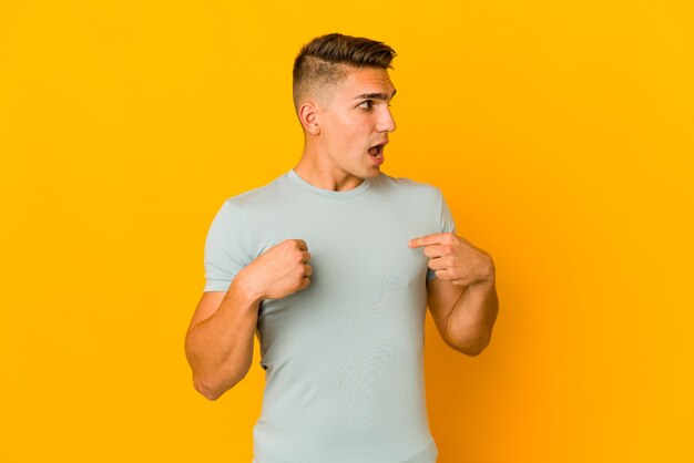 Hombre guapo joven aislado sorprendido señalando con el dedo, sonriendo ampliamente