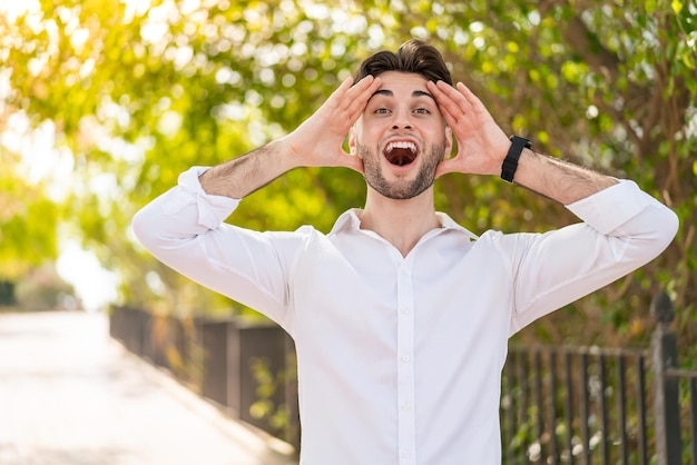 Hombre guapo joven al aire libre con expresión de sorpresa