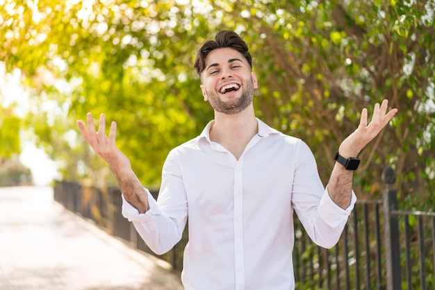 Hombre guapo joven al aire libre sonriendo mucho