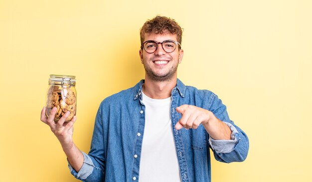 Hombre guapo joven apuntando a la cámara eligiéndote. concepto de botella de galletas