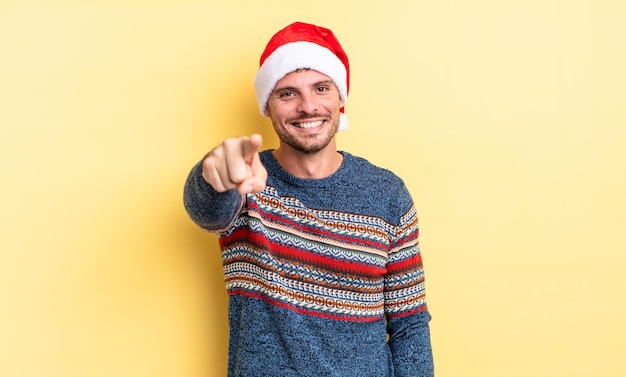 Hombre guapo joven apuntando a la cámara eligiéndote. concepto de navidad