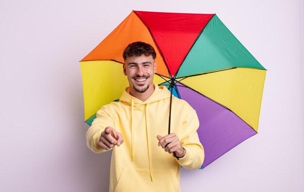 Hombre guapo joven apuntando a la cámara eligiéndote. concepto de paraguas