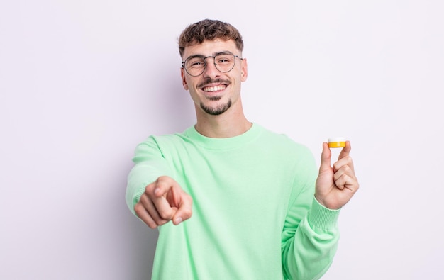 Hombre guapo joven apuntando a la cámara eligiéndote. lentes de contacto