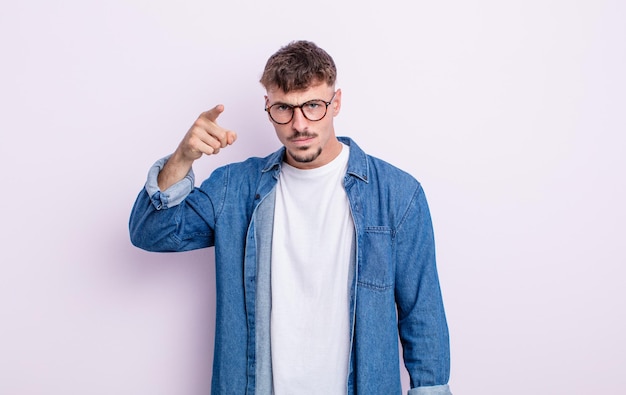 Hombre guapo joven apuntando a la cámara con una expresión agresiva enojada que parece un jefe loco y furioso