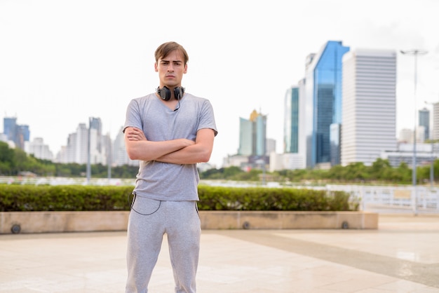 Hombre guapo joven con auriculares mientras se relaja en el parque