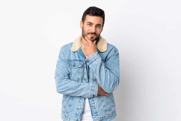 Hombre guapo joven con barba aislado en el pensamiento de la pared blanca