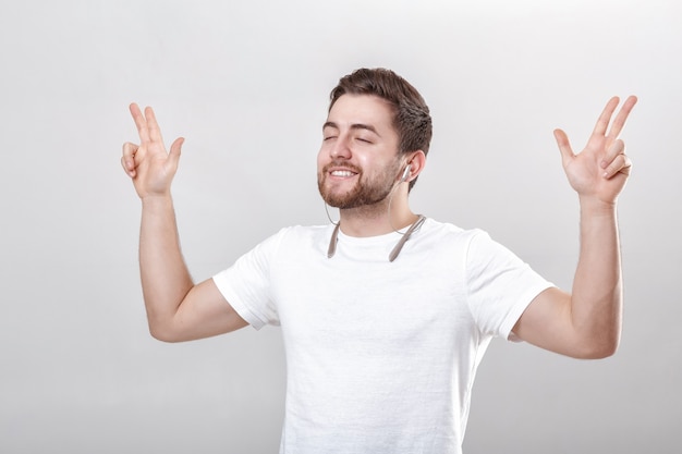 Hombre guapo joven con barba en camiseta escuchando música en auriculares