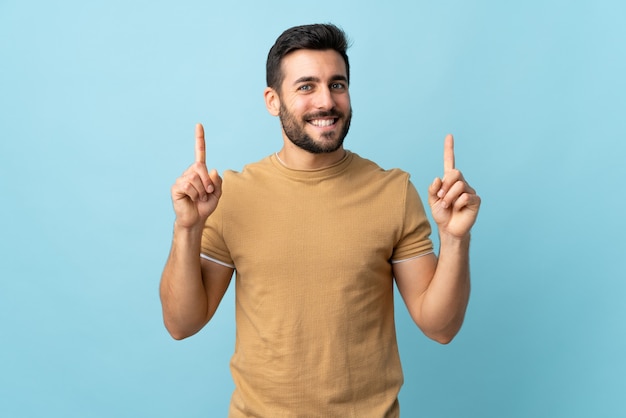 Hombre guapo joven con barba sobre fondo aislado apuntando hacia una gran idea